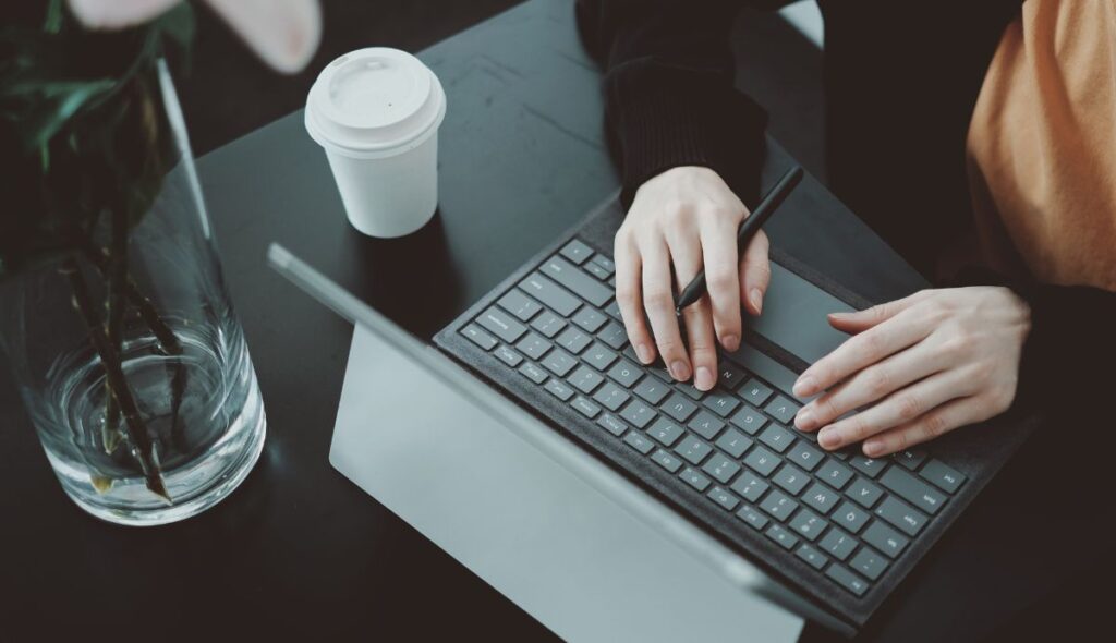 Femme travaillant à une table dans un café avec une tablette, un stylo intelligent et un clavier Folio